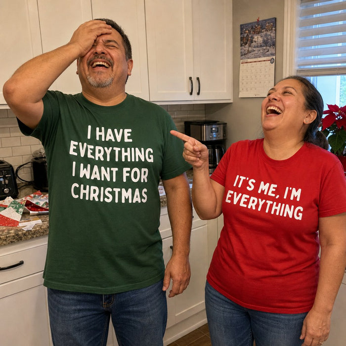 A couple laughing together in their kitchen wearing the matching tees