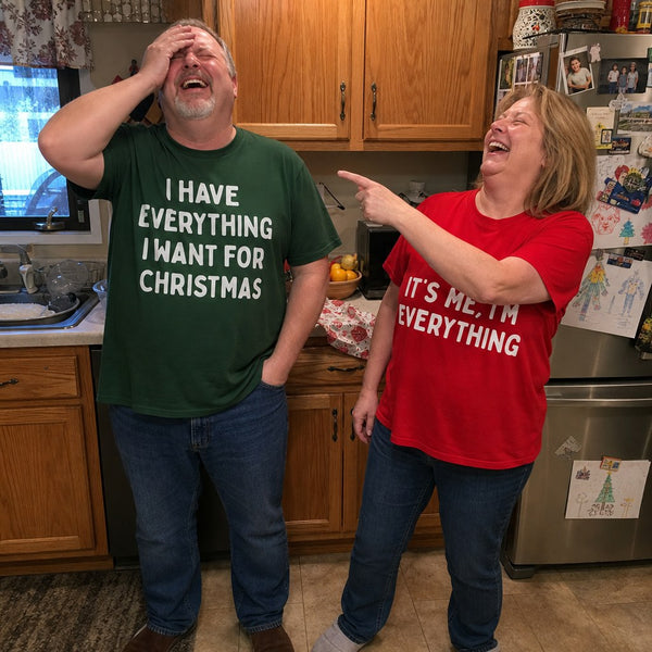 A couple laughing in their kitchen wearing the matching tees