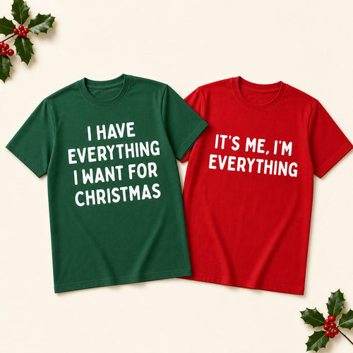 The matching green and red Christmas couples tees laid side by side on a cream background